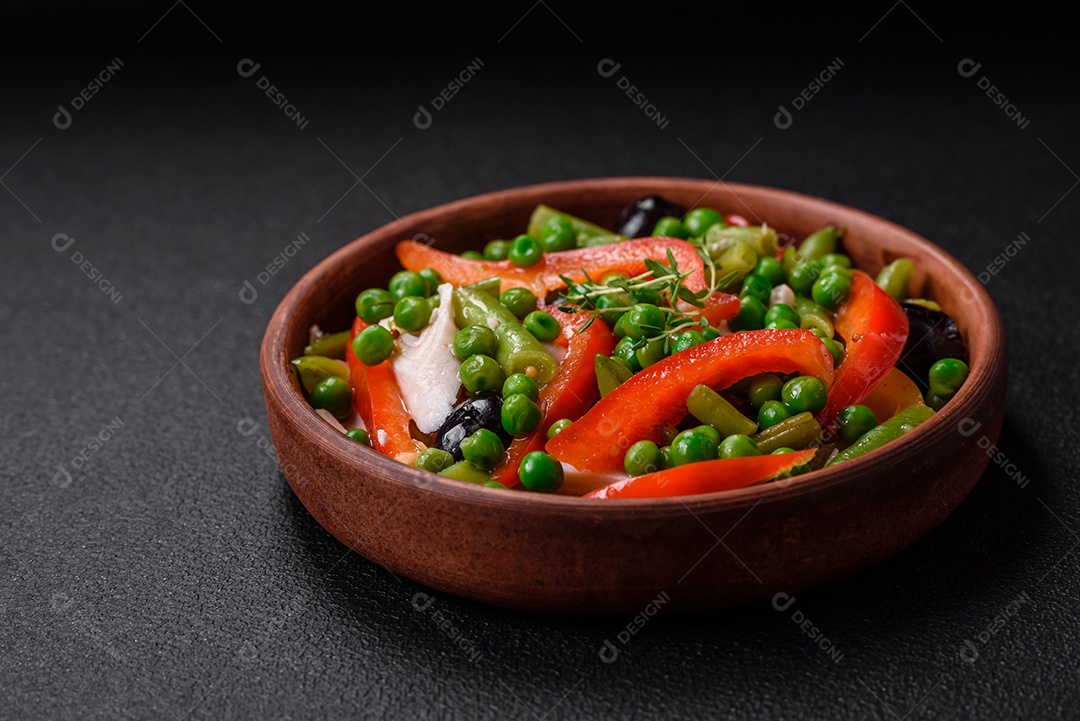 Deliciosa salada fresca de feijão verde, ervilha, pimentão e queijo com sal e especiarias sobre um fundo escuro de concreto