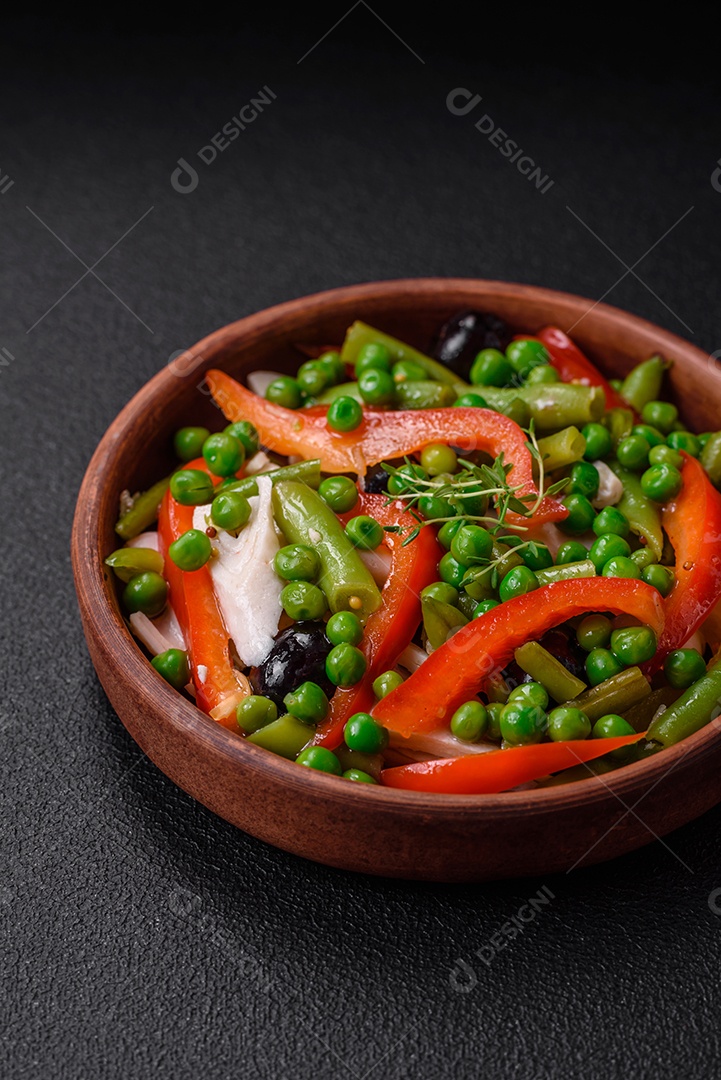 Deliciosa salada fresca de feijão verde, ervilha, pimentão e queijo com sal e especiarias sobre um fundo escuro de concreto