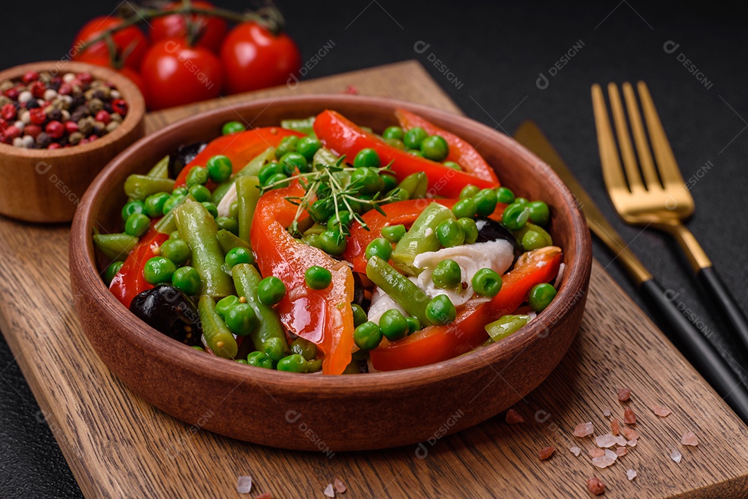 Deliciosa salada fresca de feijão verde, ervilha, pimentão e queijo com sal e especiarias sobre um fundo escuro de concreto