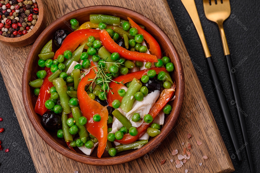Deliciosa salada fresca de feijão verde, ervilha, pimentão e queijo com sal e especiarias sobre um fundo escuro de concreto
