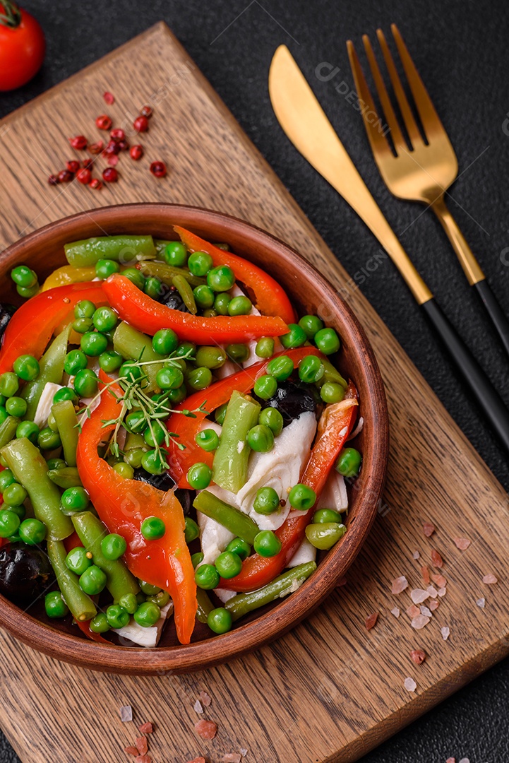 Deliciosa salada fresca de feijão verde, ervilha, pimentão e queijo com sal e especiarias sobre um fundo escuro de concreto