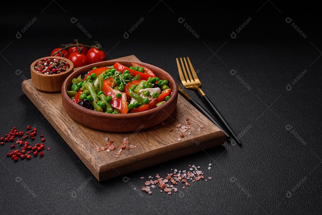Deliciosa salada fresca de feijão verde, ervilha, pimentão e queijo com sal e especiarias sobre um fundo escuro de concreto