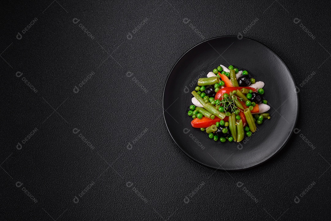 Deliciosa salada fresca de feijão verde, ervilha, pimentão e queijo com sal e especiarias sobre um fundo escuro de concreto