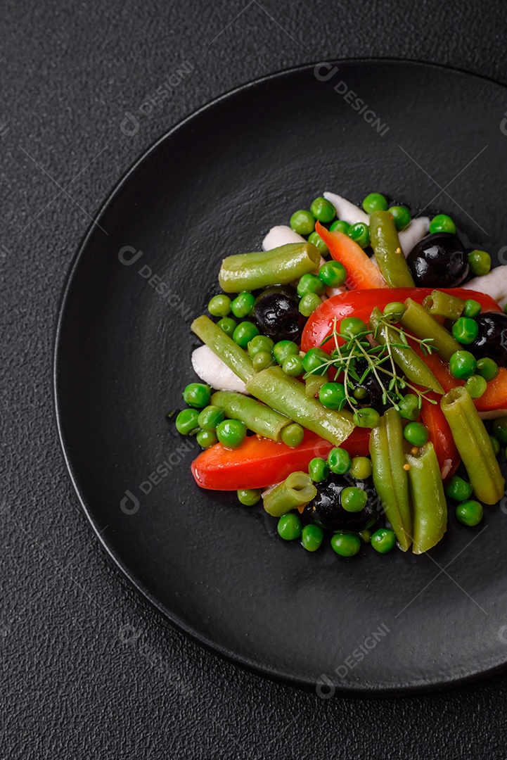 Deliciosa salada fresca de feijão verde, ervilha, pimentão e queijo com sal e especiarias sobre um fundo escuro de concreto