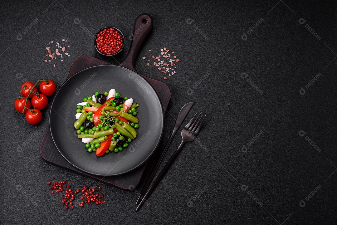 Deliciosa salada fresca de feijão verde, ervilha, pimentão e queijo com sal e especiarias sobre um fundo escuro de concreto