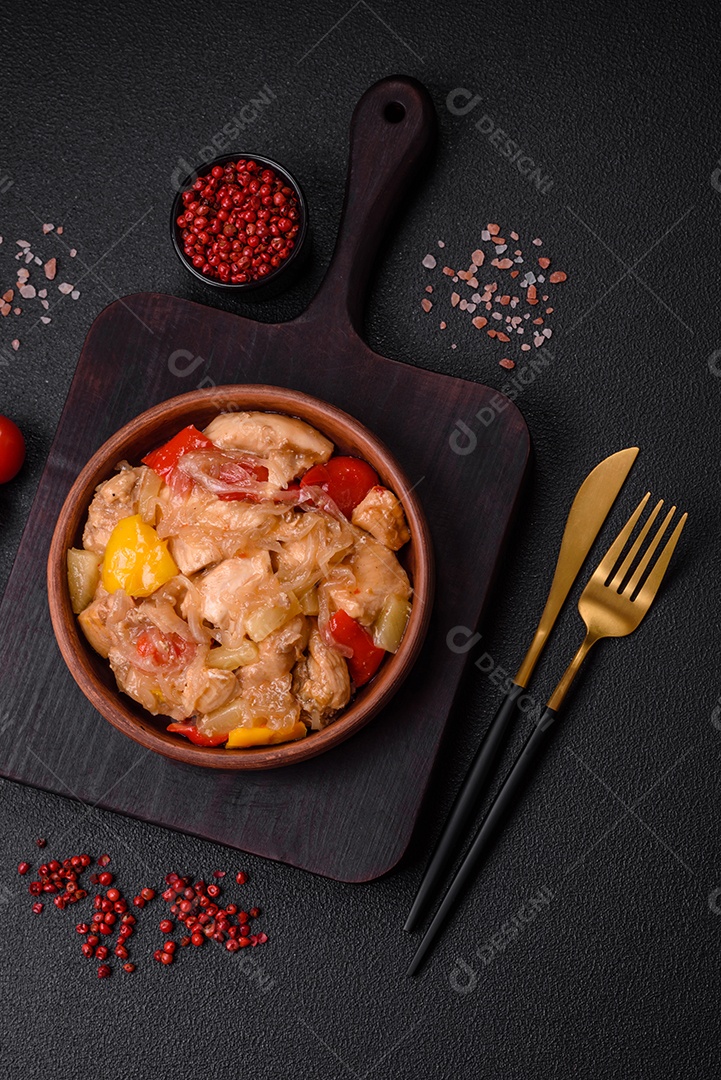 Um delicioso prato composto por fatias de frango, pimentão e cebola com sal e especiarias sobre um fundo escuro de concreto