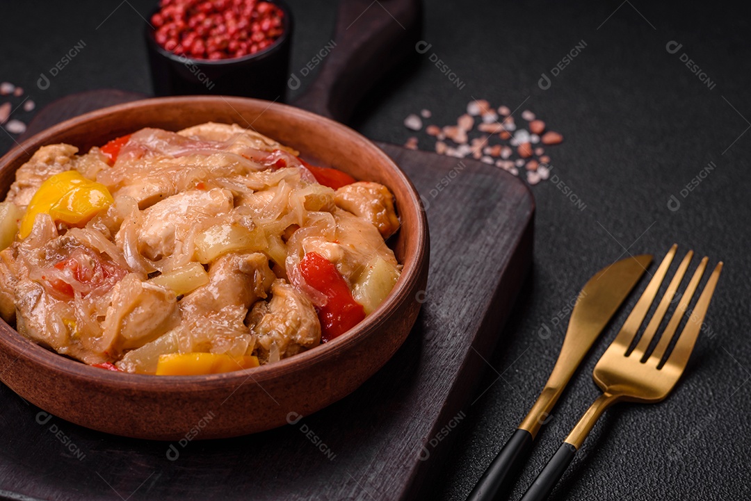 Um delicioso prato composto por fatias de frango, pimentão e cebola com sal e especiarias sobre um fundo escuro de concreto