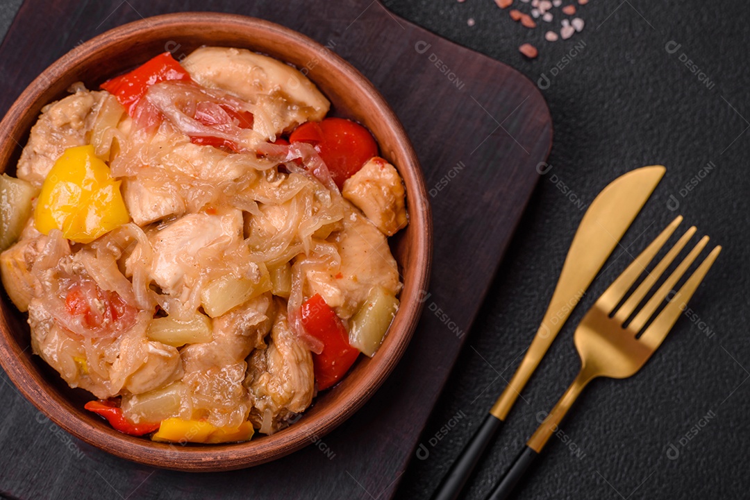 Um delicioso prato composto por fatias de frango, pimentão e cebola com sal e especiarias sobre um fundo escuro de concreto