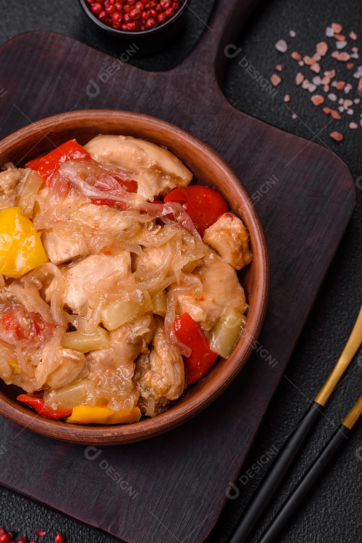 Um delicioso prato composto por fatias de frango, pimentão e cebola com sal e especiarias sobre um fundo escuro de concreto