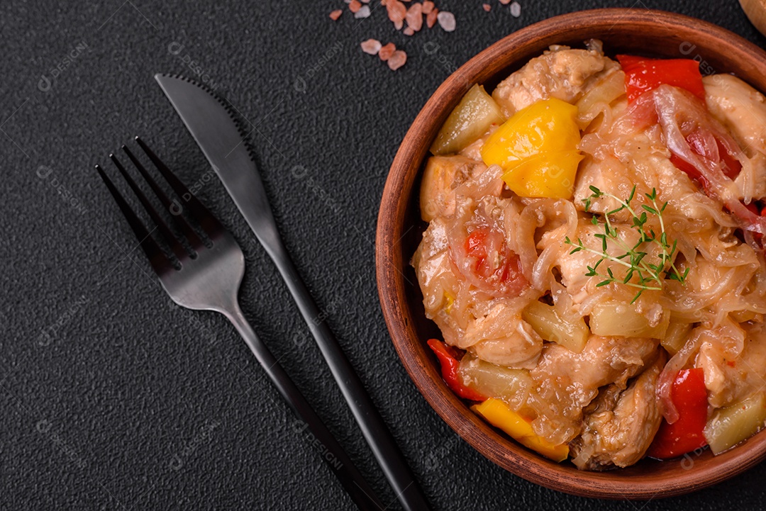 Um delicioso prato composto por fatias de frango, pimentão e cebola com sal e especiarias sobre um fundo escuro de concreto