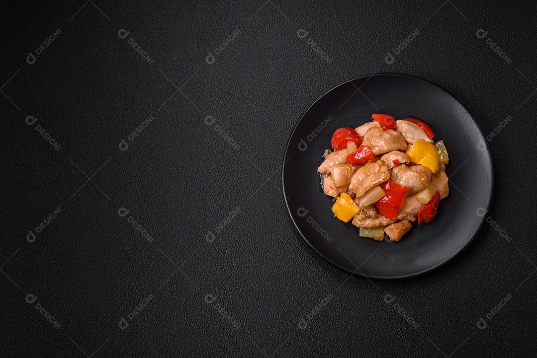 Um delicioso prato composto por fatias de frango, pimentão e cebola com sal e especiarias sobre um fundo escuro de concreto