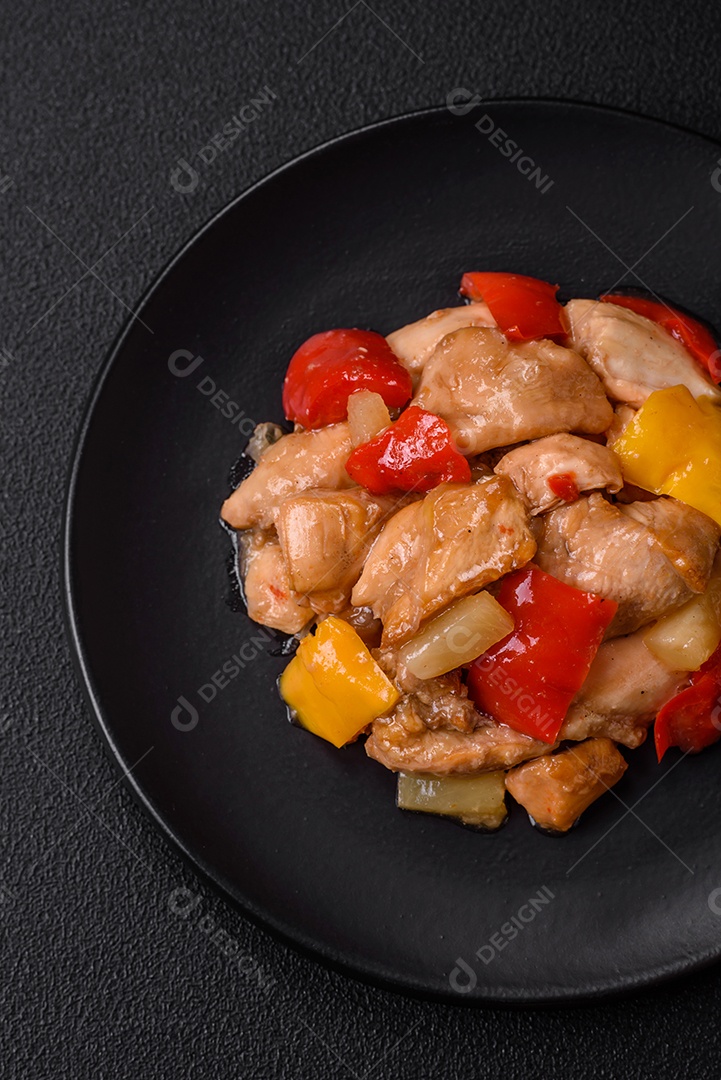 Um delicioso prato composto por fatias de frango, pimentão e cebola com sal e especiarias sobre um fundo escuro de concreto