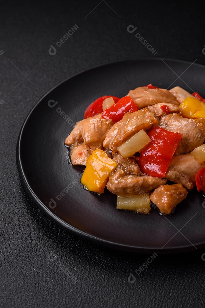 Um delicioso prato composto por fatias de frango, pimentão e cebola com sal e especiarias sobre um fundo escuro de concreto