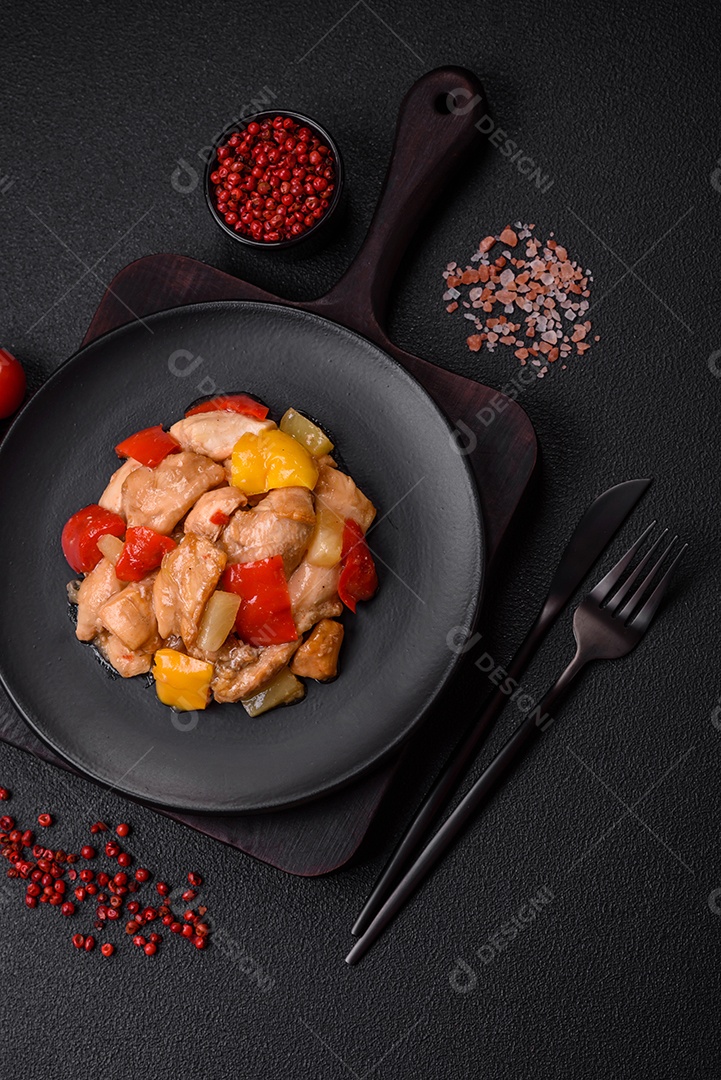 Um delicioso prato composto por fatias de frango, pimentão e cebola com sal e especiarias sobre um fundo escuro de concreto