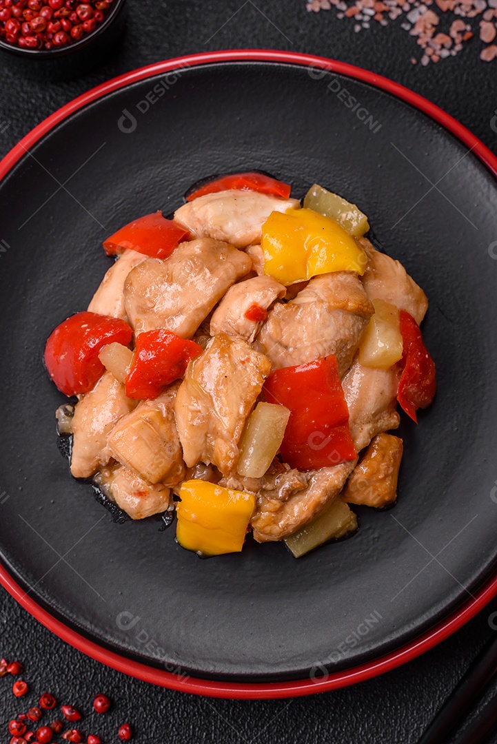 Um delicioso prato composto por fatias de frango, pimentão e cebola com sal e especiarias sobre um fundo escuro de concreto