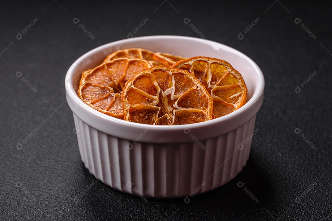 Fatias redondas secas de tangerina, laranja ou limão sobre um fundo escuro de concreto. Ingrediente para fazer doces