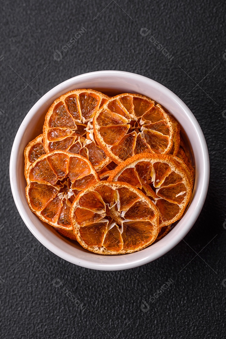 Fatias redondas secas de tangerina, laranja ou limão sobre um fundo escuro de concreto. Ingrediente para fazer doces