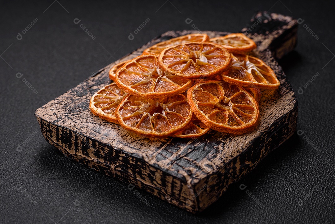 Fatias redondas secas de tangerina, laranja ou limão sobre um fundo escuro de concreto. Ingrediente para fazer doces