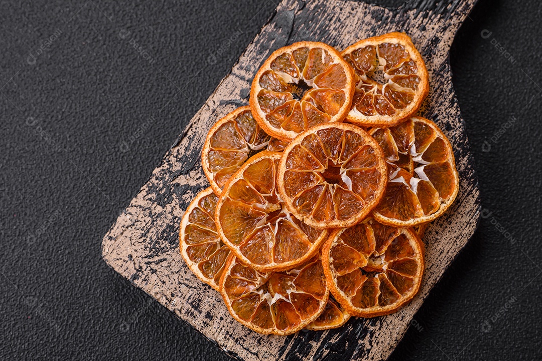 Fatias redondas secas de tangerina, laranja ou limão sobre um fundo escuro de concreto. Ingrediente para fazer doces