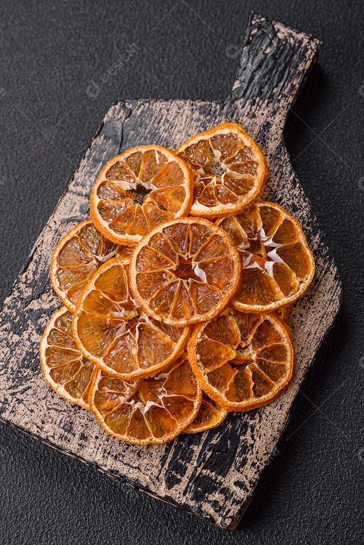 Fatias redondas secas de tangerina, laranja ou limão sobre um fundo escuro de concreto. Ingrediente para fazer doces