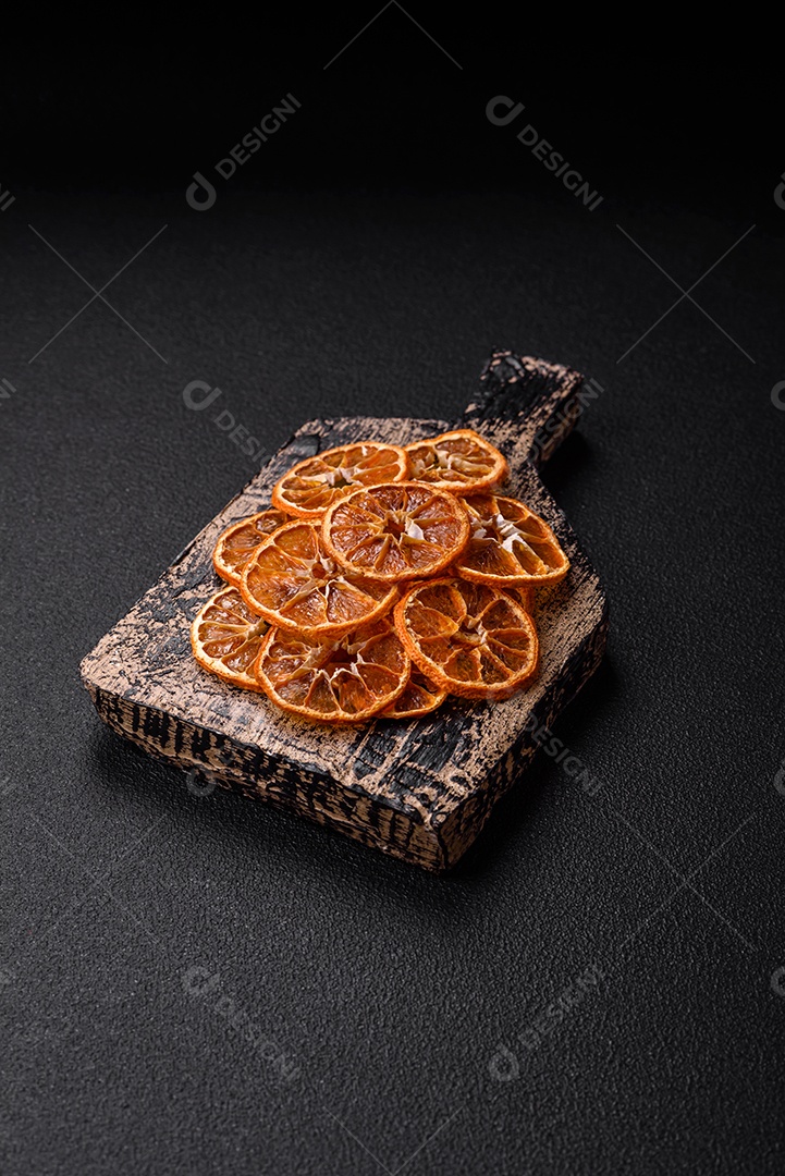 Fatias redondas secas de tangerina, laranja ou limão sobre um fundo escuro de concreto. Ingrediente para fazer doces