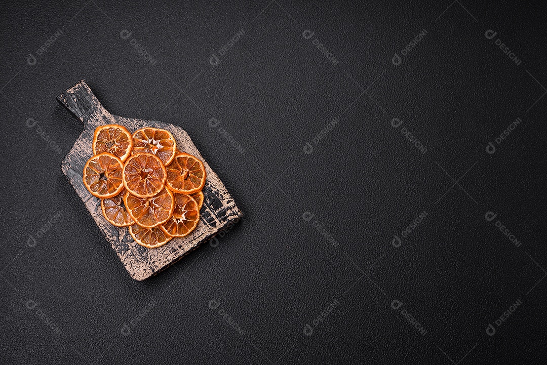 Fatias redondas secas de tangerina, laranja ou limão sobre um fundo escuro de concreto. Ingrediente para fazer doces