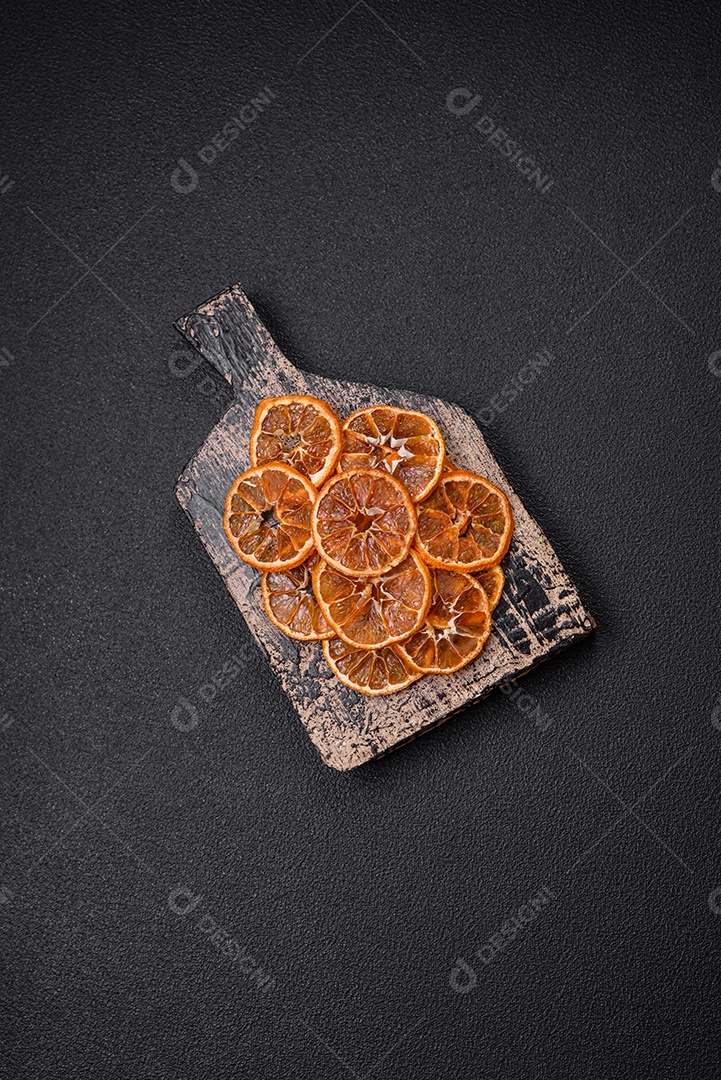 Fatias redondas secas de tangerina, laranja ou limão sobre um fundo escuro de concreto. Ingrediente para fazer doces
