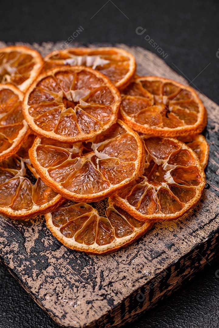 Fatias redondas secas de tangerina, laranja ou limão sobre um fundo escuro de concreto. Ingrediente para fazer doces