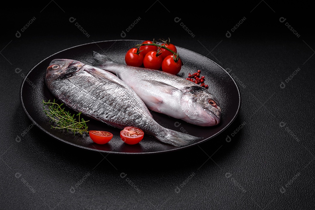 Peixe dorada cru fresco com sal, especiarias e ervas sobre um fundo escuro de concreto
