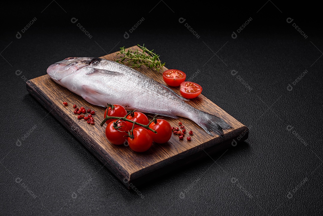 Peixe dorada cru fresco com sal, especiarias e ervas sobre um fundo escuro de concreto