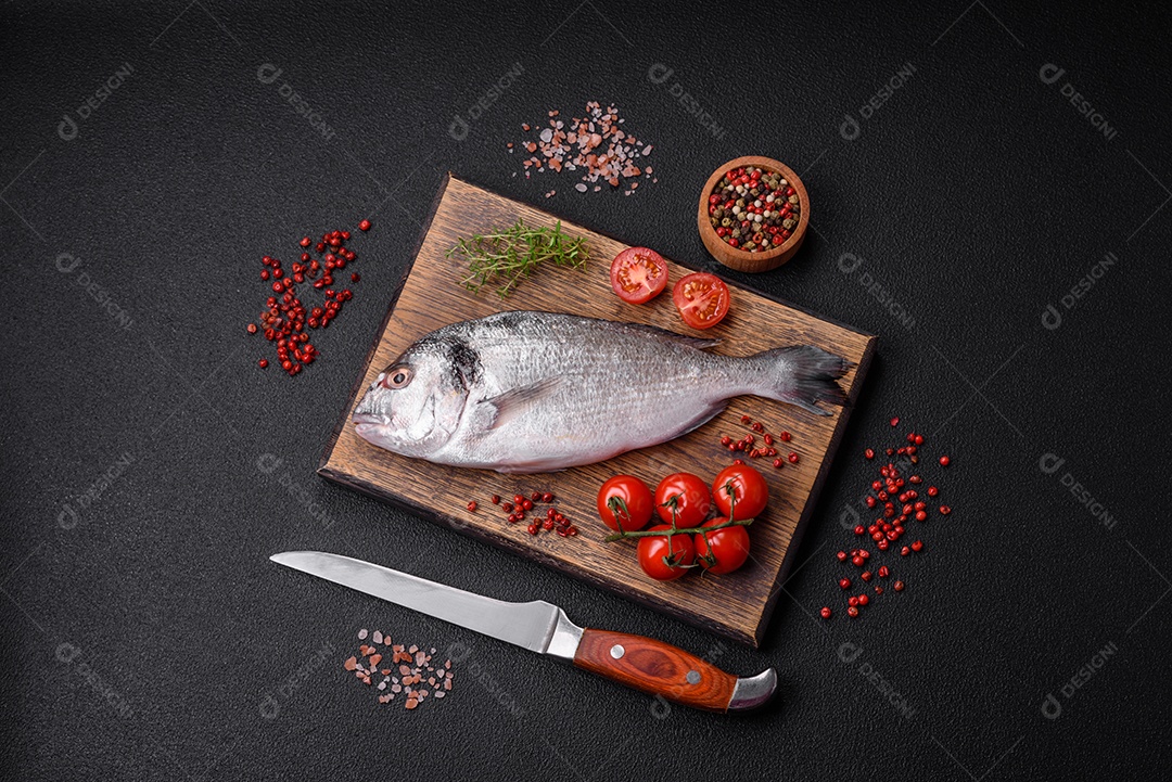 Peixe dorada cru fresco com sal, especiarias e ervas sobre um fundo escuro de concreto