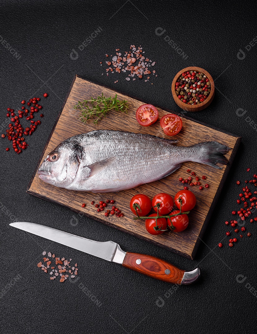 Peixe dorada cru fresco com sal, especiarias e ervas sobre um fundo escuro de concreto