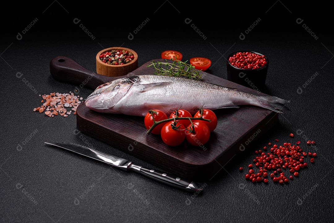 Peixe dorada cru fresco com sal, especiarias e ervas sobre um fundo escuro de concreto