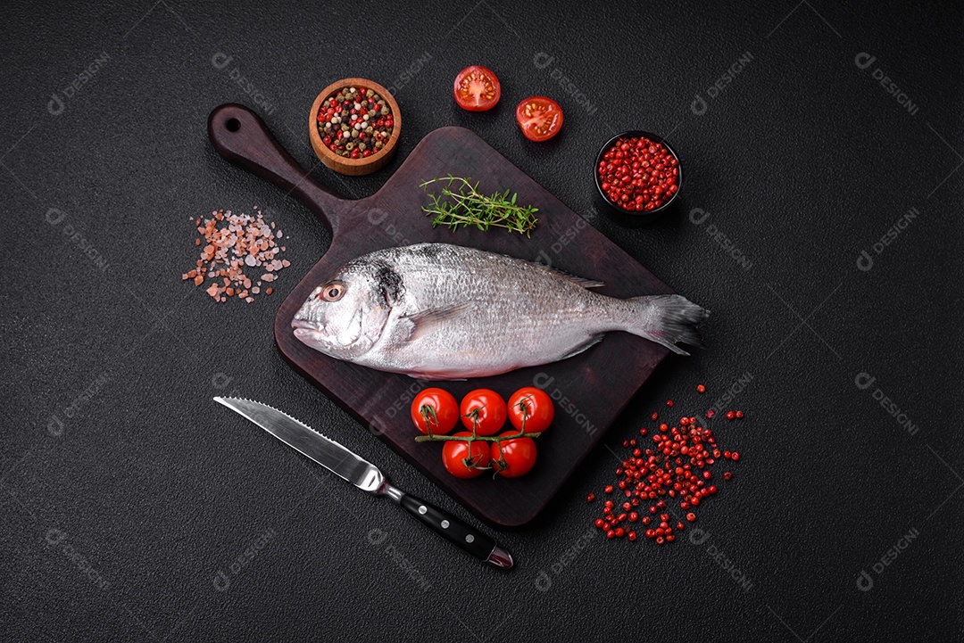 Peixe dorada cru fresco com sal, especiarias e ervas sobre um fundo escuro de concreto