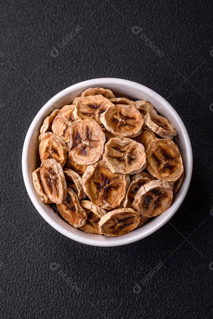 Fatias redondas de banana doce em um fundo escuro de concreto. Ingredientes para fazer doces veganos