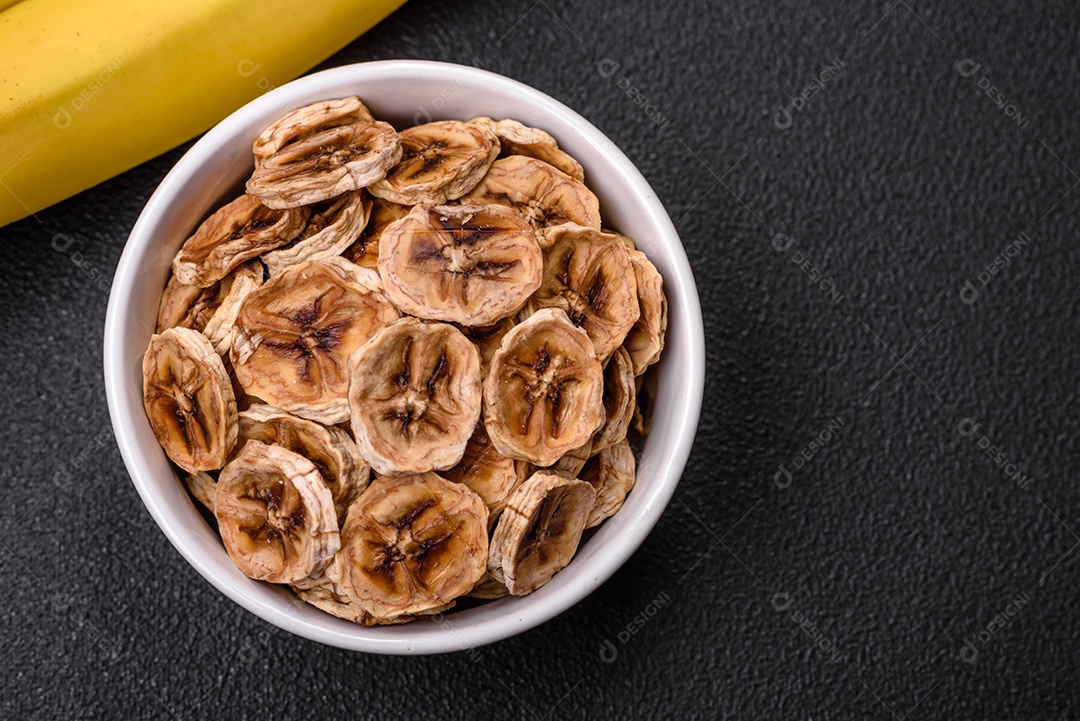 Fatias redondas de banana doce em um fundo escuro de concreto. Ingredientes para fazer doces veganos