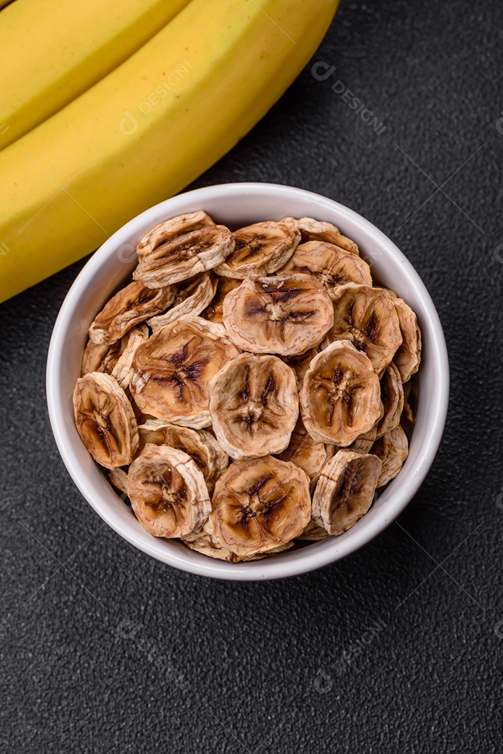 Fatias redondas de banana doce em um fundo escuro de concreto. Ingredientes para fazer doces veganos