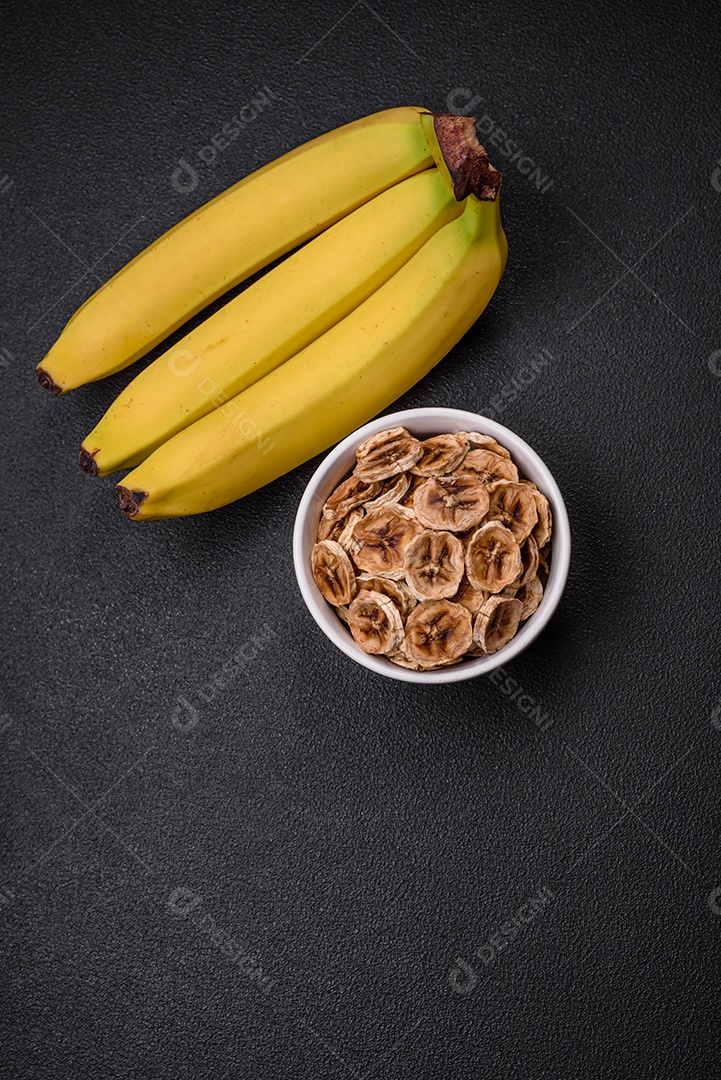 Fatias redondas de banana doce em um fundo escuro de concreto. Ingredientes para fazer doces veganos