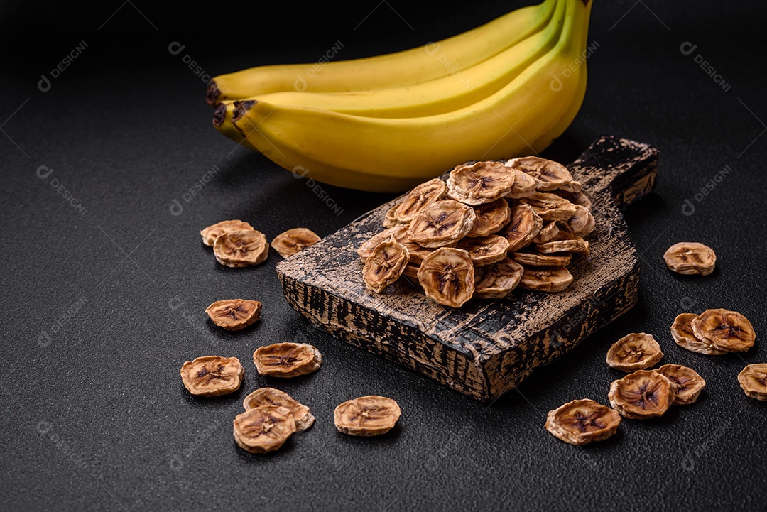 Fatias redondas de banana doce em um fundo escuro de concreto. Ingredientes para fazer doces veganos