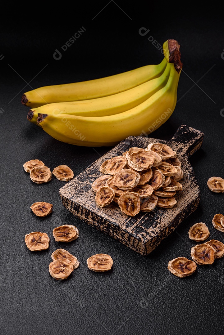 Fatias redondas de banana doce em um fundo escuro de concreto. Ingredientes para fazer doces veganos