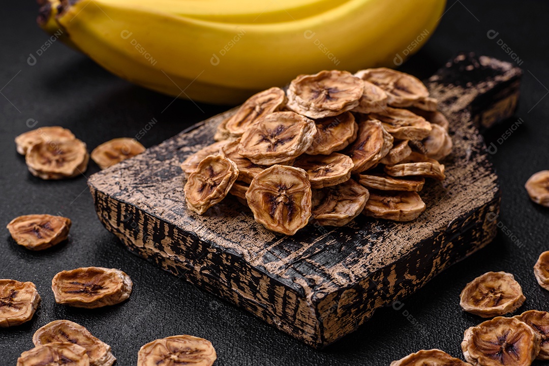 Fatias redondas de banana doce em um fundo escuro de concreto. Ingredientes para fazer doces veganos