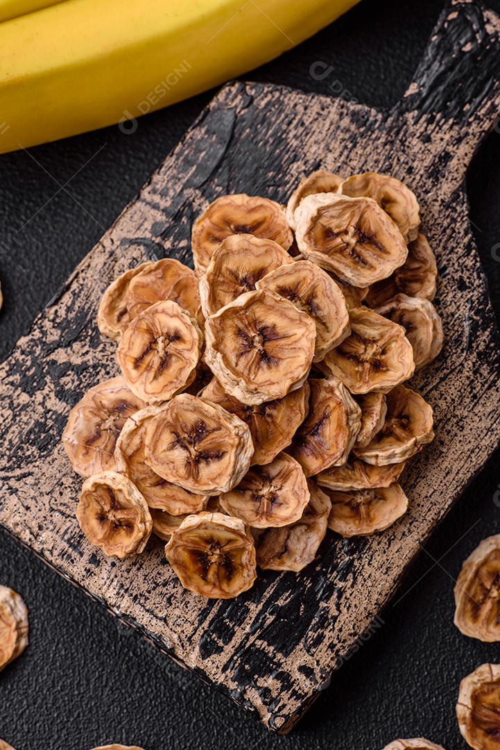 Fatias redondas de banana doce em um fundo escuro de concreto. Ingredientes para fazer doces veganos