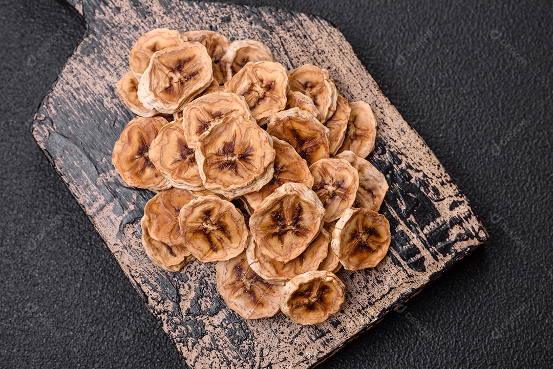 Fatias redondas de banana doce em um fundo escuro de concreto. Ingredientes para fazer doces veganos