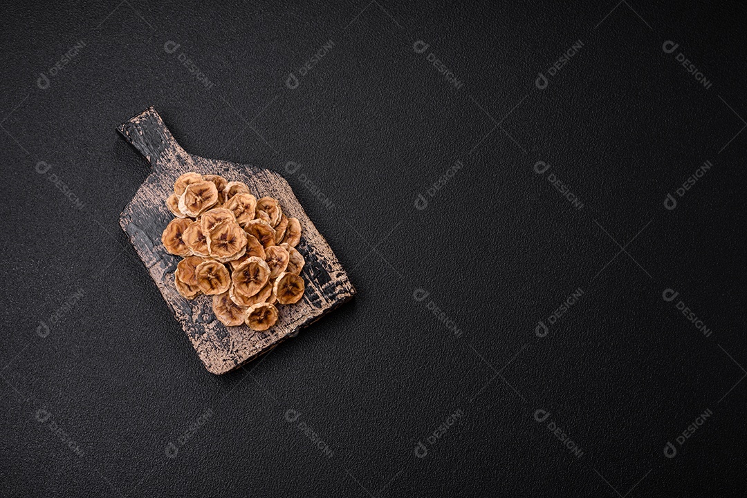 Fatias redondas de banana doce em um fundo escuro de concreto. Ingredientes para fazer doces veganos
