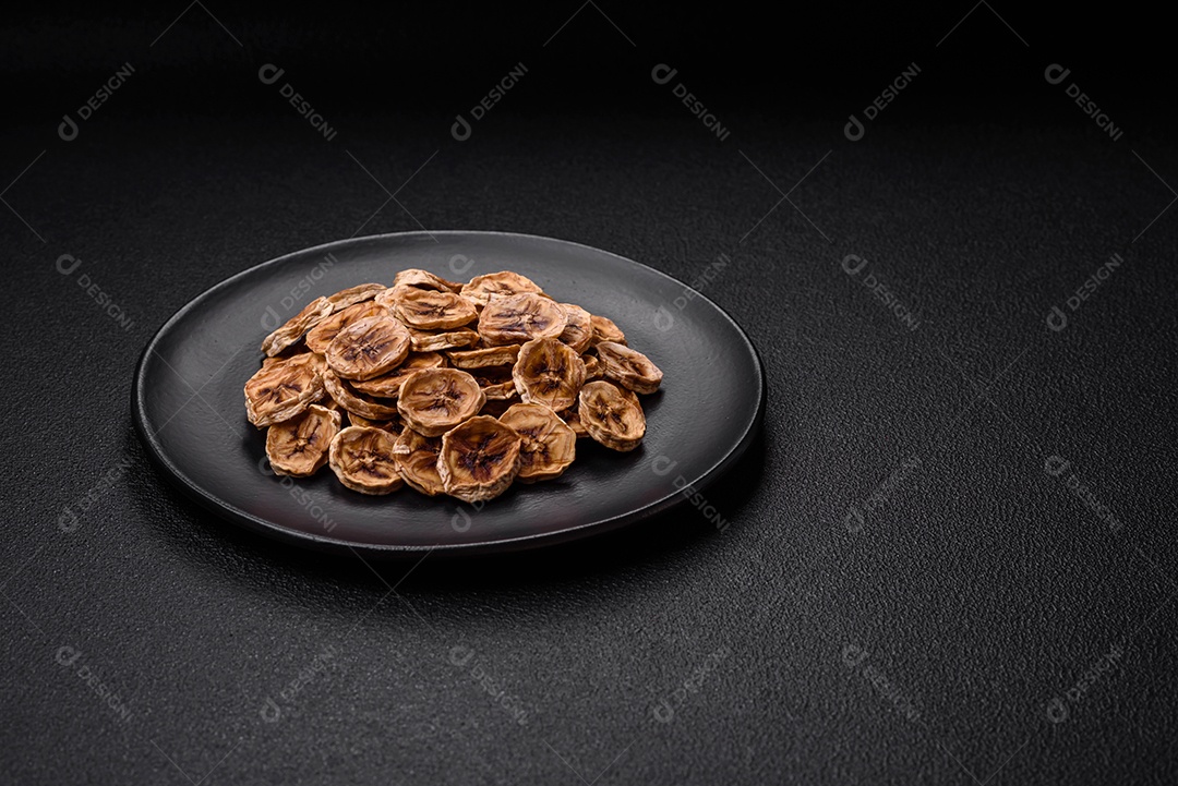 Fatias redondas de banana doce em um fundo escuro de concreto. Ingredientes para fazer doces veganos