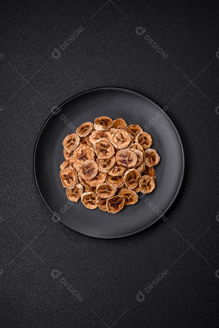 Fatias redondas de banana doce em um fundo escuro de concreto. Ingredientes para fazer doces veganos