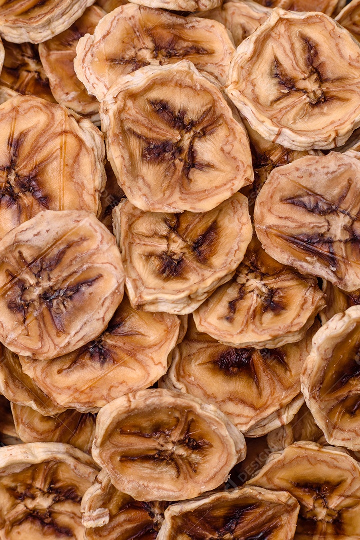 Fatias redondas de banana doce em um fundo escuro de concreto. Ingredientes para fazer doces veganos