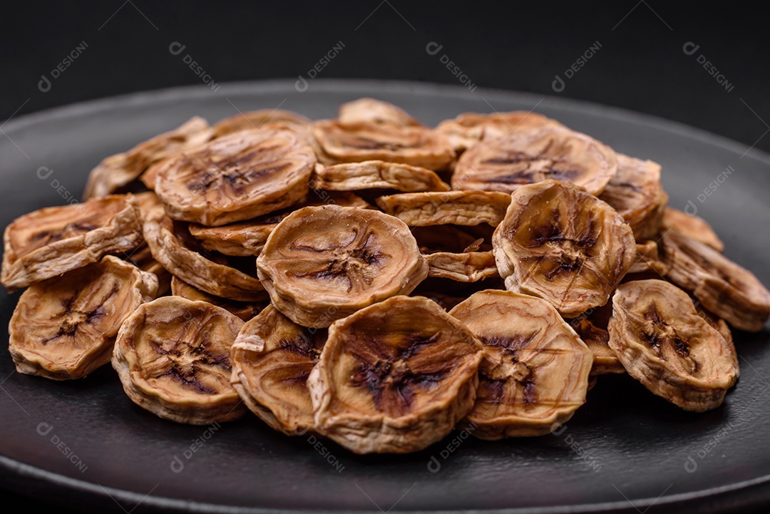 Fatias redondas de banana doce em um fundo escuro de concreto. Ingredientes para fazer doces veganos