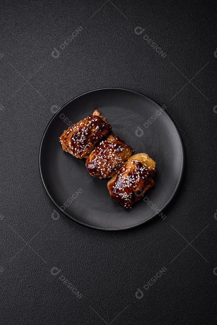 Delicioso frango frito suculento com molho teriyaki agridoce e sementes de gergelim em um fundo escuro de concreto