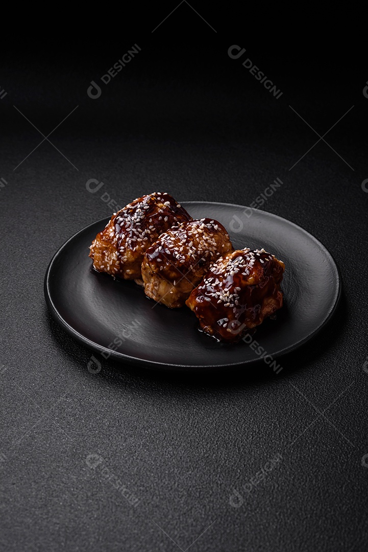 Delicioso frango frito suculento com molho teriyaki agridoce e sementes de gergelim em um fundo escuro de concreto